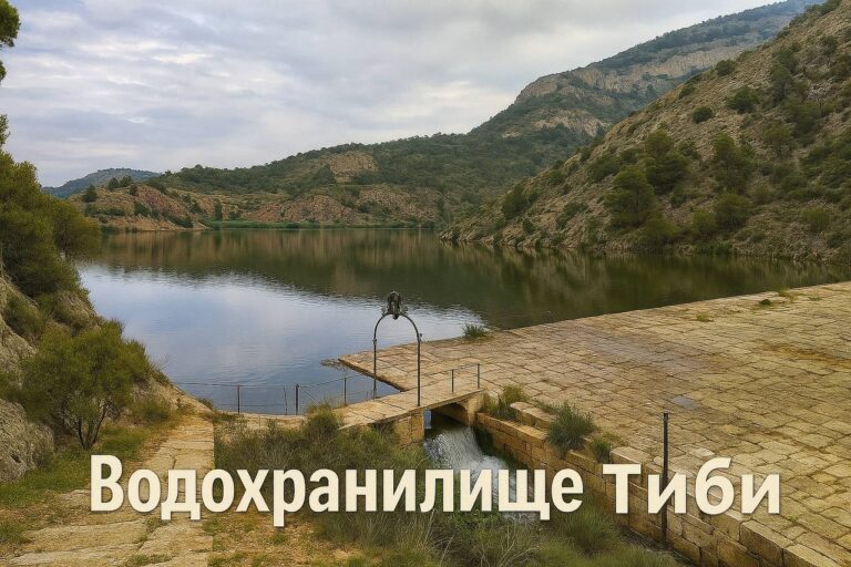 Реалистичное фото водохранилища Тиби (Pantano de Tibi) в горах Аликанте, Испания: отражение облаков в спокойной воде, старинная каменная плотина XVI века, окружённая зелёными склонами и природой.