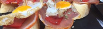 Тапас на шпажках: ломтики хамона, перепелиное яйцо и оливки на кусочках хлеба