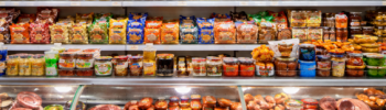 Прилавок магазина восточно-европейских продуктов с колбасами, соленьями и консервами