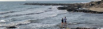 Скалистое побережье Кальпе с морскими волнами, людьми у воды и горным силуэтом на фоне Средиземного моря